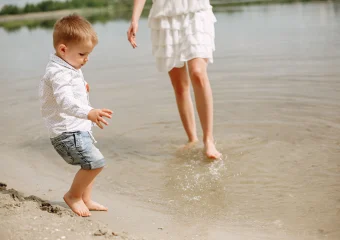 Niño caminando en la playa descalzo, imagen ideal para hablar sobre señales ortopédicas en niños.