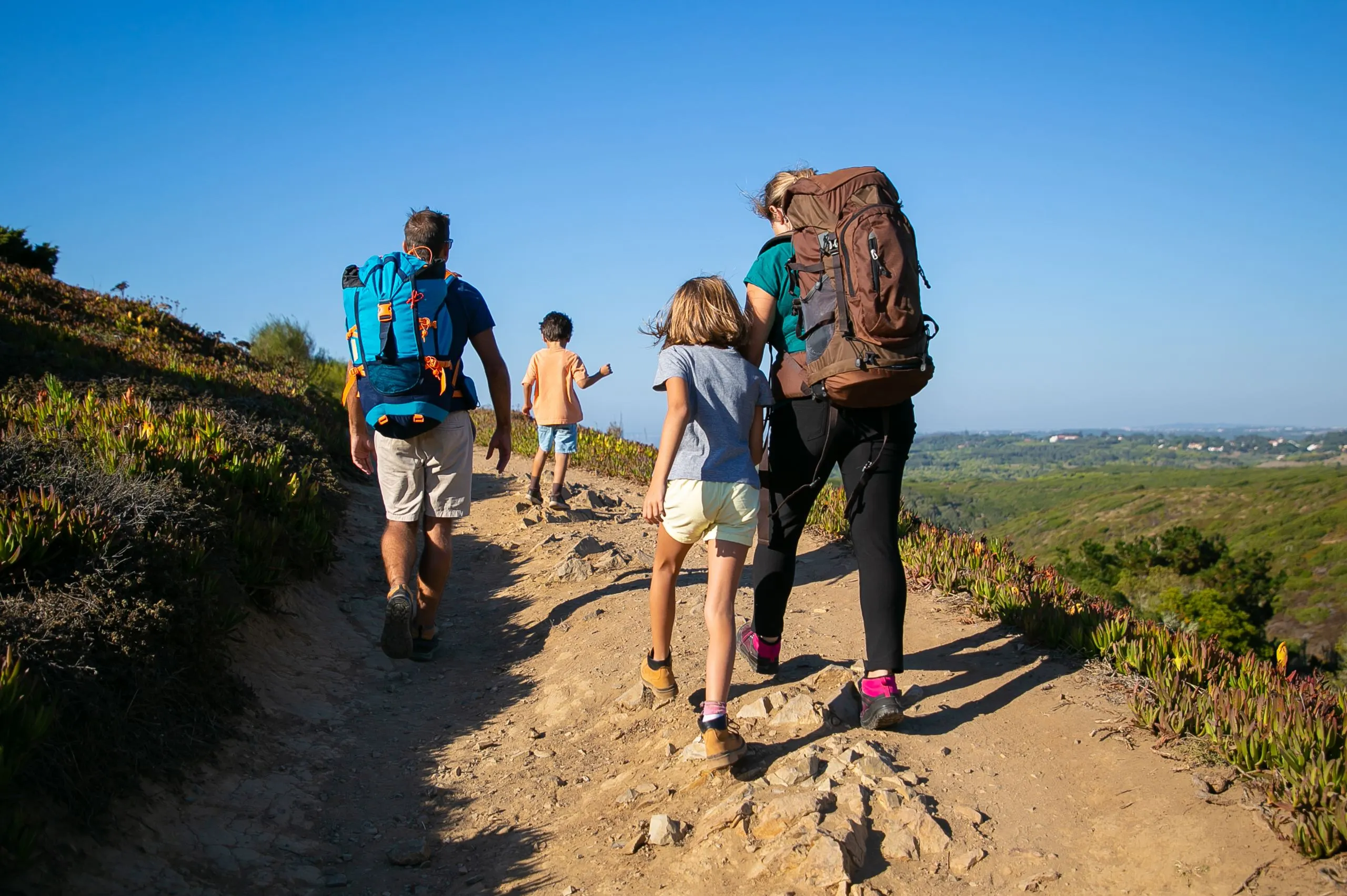 Familia caminando con mochilas adecuadas para evitar lesiones en vacaciones