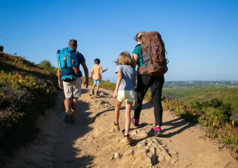 Familia caminando con mochilas adecuadas para evitar lesiones en vacaciones