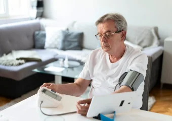 Persona mayor controlando su presión arterial y salud ósea.